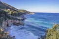 View of sea with foam waves, stone cliffs and hills covered with forests