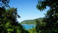 View of sea framed by greens & trees