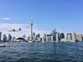 A view of the sea front at Toronto from a boat with a plane coming in to land