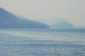 A view of a sea and mountains in haze. Smokey mountains look my