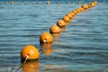 View of the sea from a shore with a long line of orange colored marker buoys floating Royalty Free Stock Photo