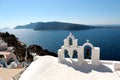 View of sea surface through traditional Greek white church arch with cross and bells in Oia village of Cyclades Island Royalty Free Stock Photo