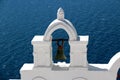 View of sea surface through traditional Greek white church arch with cross and bells in Oia village of Cyclades Island Royalty Free Stock Photo