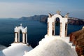 View of sea surface through traditional Greek white church arch with cross and bells in Oia village of Cyclades Island, Santorini, Royalty Free Stock Photo