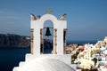 View of sea surface through traditional Greek white church arch with cross and bells in Oia village of Cyclades Island, Santorini, Royalty Free Stock Photo