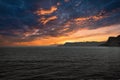 View from the sea to the West Cape in Norway at sunset with sun rays and heavy clouds Royalty Free Stock Photo