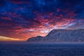 View from the sea to the West Cape in Norway at sunset with sun rays and heavy clouds Royalty Free Stock Photo