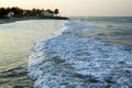 View on the sea waves with beach houses and palm trees on a background. Royalty Free Stock Photo