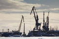 View of seaport at sunny winter day - cargo cranes in ice harbor, silhouette Royalty Free Stock Photo