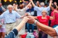 View of senior people holding hands and dancing national dance Sardana