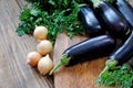 Whole raw eggplant, onions and parsley on wooden cutting board Royalty Free Stock Photo