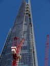 view of the Shard building against a deep blue sky with red tower cranes in the foreground