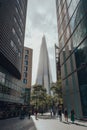 View of The Shard between the buildings on More London, London, UK, people walking in front