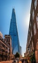 View of The SHARD - the modern skyscraper with its futuristic glass arrow spire facade form emerging between downtown buildings