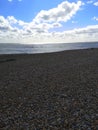 The shingle beach against a bright blue sky at Winchelsea, East Sussex, UK.