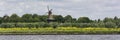 View on the shore of the Merwede River in the Netherlands. Typical Dutch landscape with traditional windmill