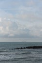 A view from the shore of a passing cargo tanker in the distance on the sea horizon