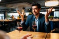 View from shoulder of unrecognizable female to surprised elegant man in suit sitting at table with glasses of red wine Royalty Free Stock Photo