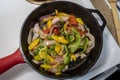 View of shrimp and peppers cooking in a cast iron skillet on a white stove top Royalty Free Stock Photo