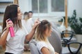 View from side of hairdresser fixing bouffant with hairspray in beauty salon