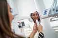 View from side of happy female patient. Woman looking at mirror and enjoying beautiful smile in dental office Royalty Free Stock Photo