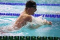 View side of man swims breaststroke in a swimming pool