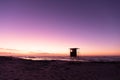 View of silhouette lifeguard hut on sandy beach against sea and clear purple sky, copy space