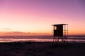 View of silhouette lifeguard hut on sandy beach against sea and purple sky, copy space