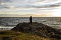 View of a silhouetted man standing the the rocky coastline on San Juan Island at sunset, with thin white clouds in the background Royalty Free Stock Photo