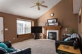 View of a simple living room with fireplace, television, sofa, couch, and a window in the brown wall