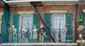 A view of skeletons adorned with Mardi Gras beads on a balcony porch