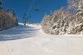 View of skiers on ski lift with snow covered mountains chairlift above ski slope