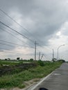 view of the sky, grass, streets, clouds and electricity poles in the village Royalty Free Stock Photo
