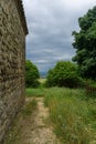 View of the sky before the rain through the trees. Stone wall of the church and earthen path. Green grass around Royalty Free Stock Photo