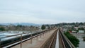 view from Sky Train window of moving train in Surrey Vancouver Canada spring no leaves bare trees stations skyscrapers