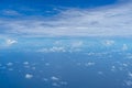 View of small abstract white cloud with bright blue sky horizon and vast sea ocean background from above flying airplane window Royalty Free Stock Photo