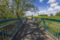 View of small bride over river on green trees and blue sky with white clouds background. Royalty Free Stock Photo