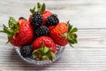 View of small glass bowl full of strawberries and blackberries. Royalty Free Stock Photo