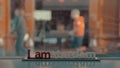 View of small plastic figure of Iamsterdam letters sculpture on the bridge against blurred cityscape, Amsterdam