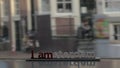 View of small plastic figure of Iamsterdam letters sculpture on the bridge against blurred cityscape, Amsterdam