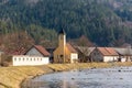 View of small village near the river, with typical architecture and small church. Forest and trees in the background. Countryside