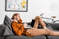 View of smiling 3d artist using laptop near vr headset on couch in office