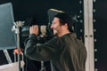 View of smiling handsome cameraman working in photo studio