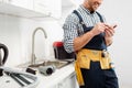 View of smiling plumber using smartphone