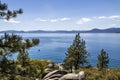 View of smooth rocks on shore of Lake Tahoe and beautiful view across the water with kayak rowing and mountains in the distance