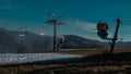 View of snow cannons or artificial snow makers on a ski slope on a sunny day. Visible partly covered ski slope with snow and some