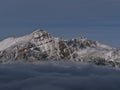 View of the snow-capped peak of rugged mountain Franchere Peak above sea of clouds in Jasper National Park, Canada in late autumn. Royalty Free Stock Photo