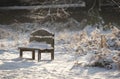 A view of a snow covered empty bench in the grounds of the Elizabethan Wollaton Hall museum and gardens in the snow in winter in Royalty Free Stock Photo