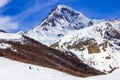 View of the snow-covered Kazbek, a group of skiers rises to the top