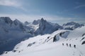 a view of the snow-covered mountain range, with skiers, snowboarders and snowshoe trekkers in action